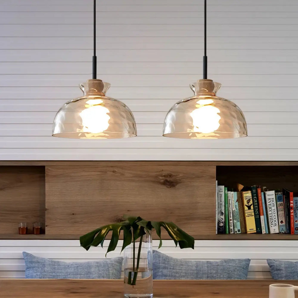 Suspension luminaire tukai avec deux abat-jours en verre texturé ton chaud suspendus au-dessus d’une table en bois