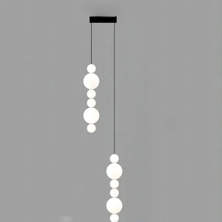 Suspension luminaire oxyo avec chutes verticales de boules opalines en verre dépoli et support de plafond noir élégant