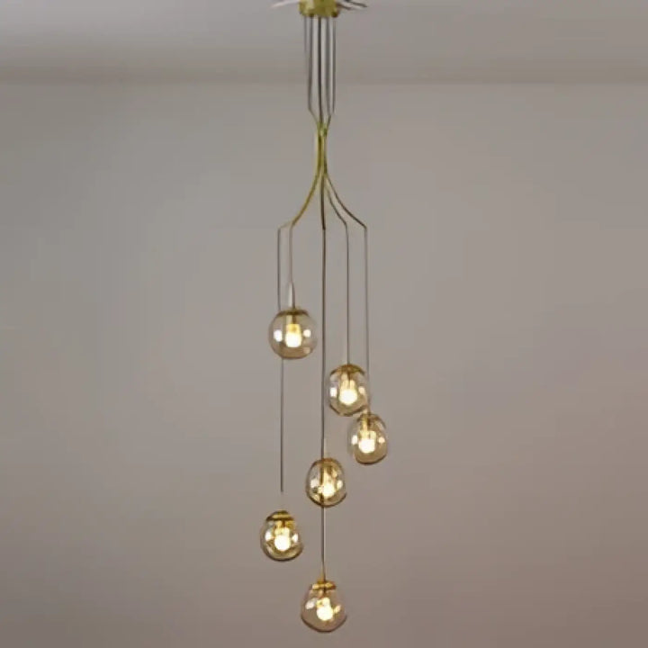 Suspension luminaire umami en métal doré avec plusieurs globes en verre sphériques suspendus à un support central