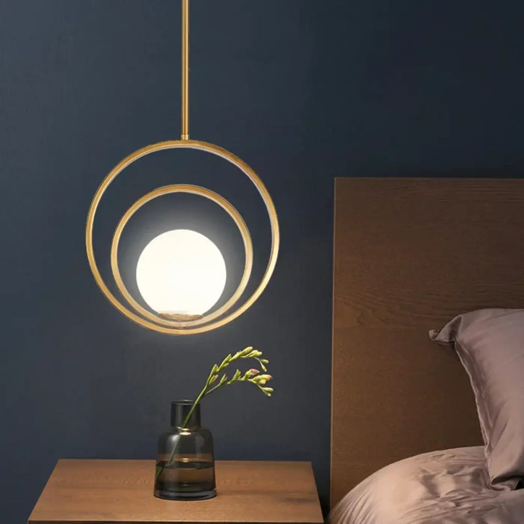 Suspension luminaire élégante lumienia en ton or avec deux anneaux concentriques et ampoule sphérique lumineuse