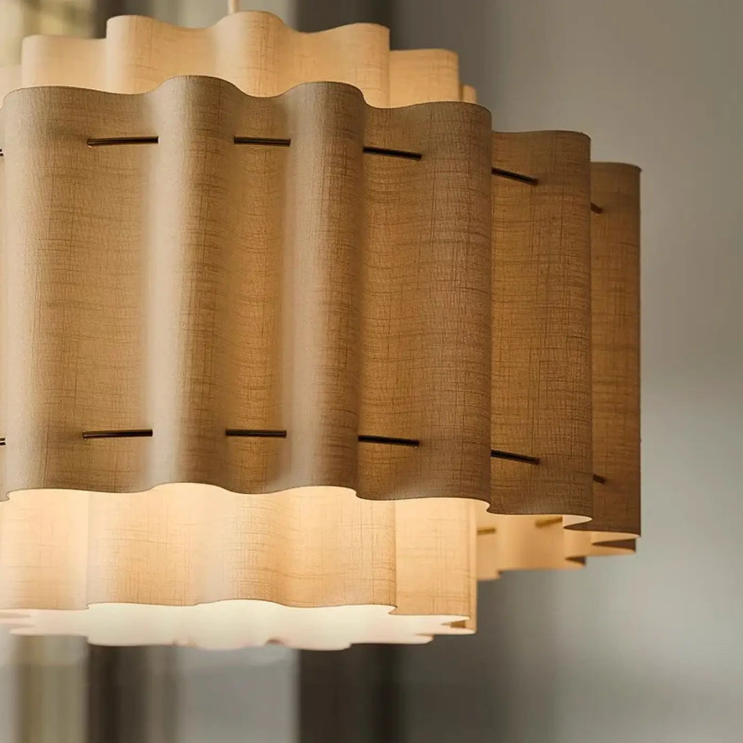 Suspension luminaire wabi en tissu beige tissé avec sections cylindriques ondulées superposées et accents métalliques foncés