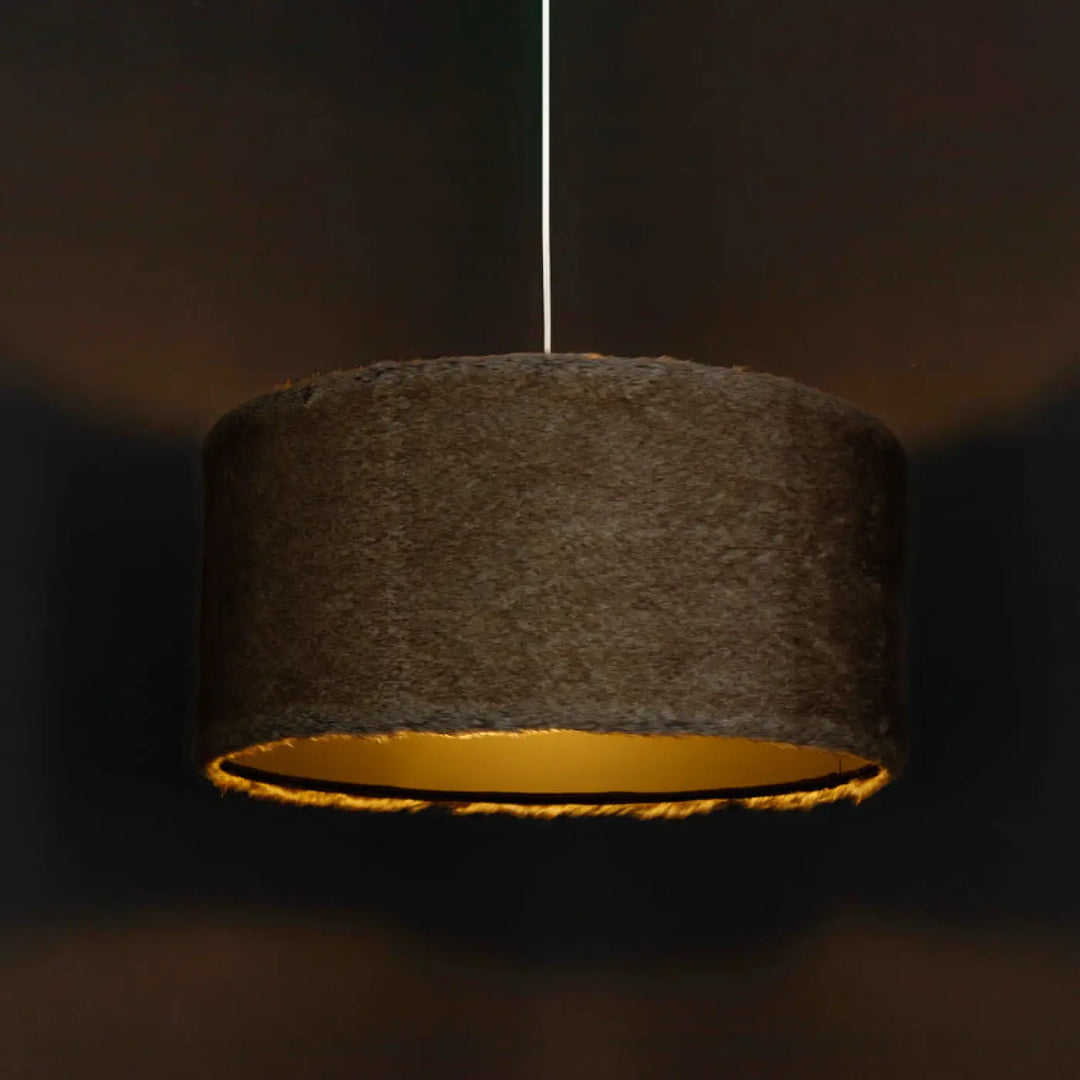 Suspension luminaire bear light cylindrique marron foncé avec doublure intérieure or chaud associée à une fausse fourrure beige