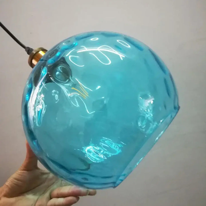 Suspension luminaire glassio en verre turquoise translucide à surface facettée avec fixation en métal couleur laiton pour ambiance chaleureuse