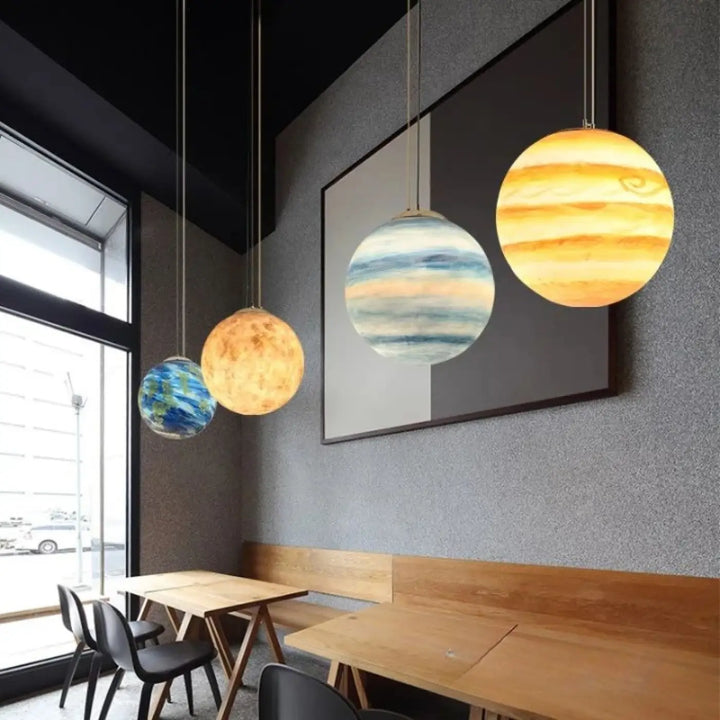 Suspension luminaire cosimo avec trois suspensions sphériques aux motifs planétaires pour un éclairage doux qui invite à l’évasion