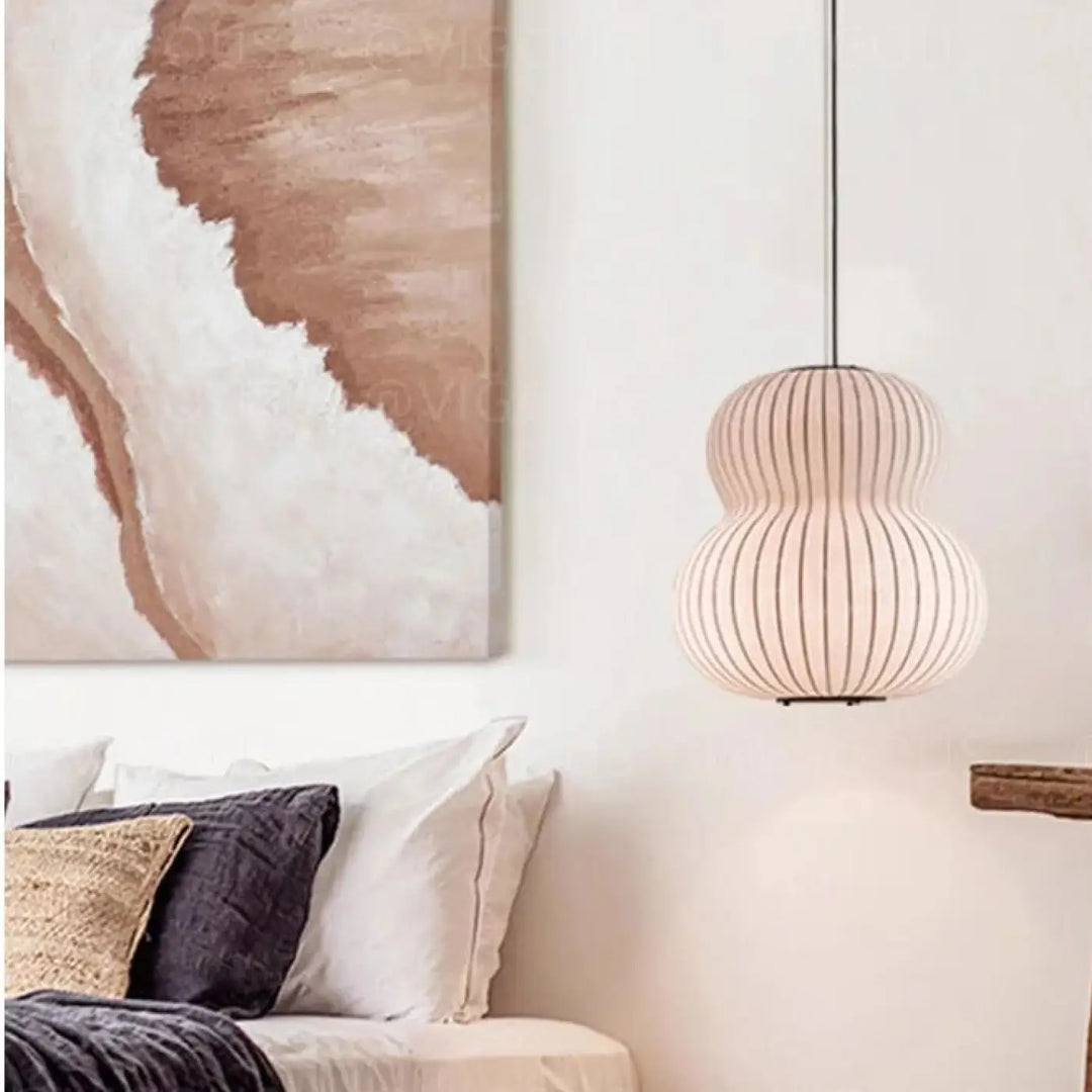 Une lampe à pendentif beige et côtelée, au design en forme de gourde, est suspendue à un fin cordon noir.