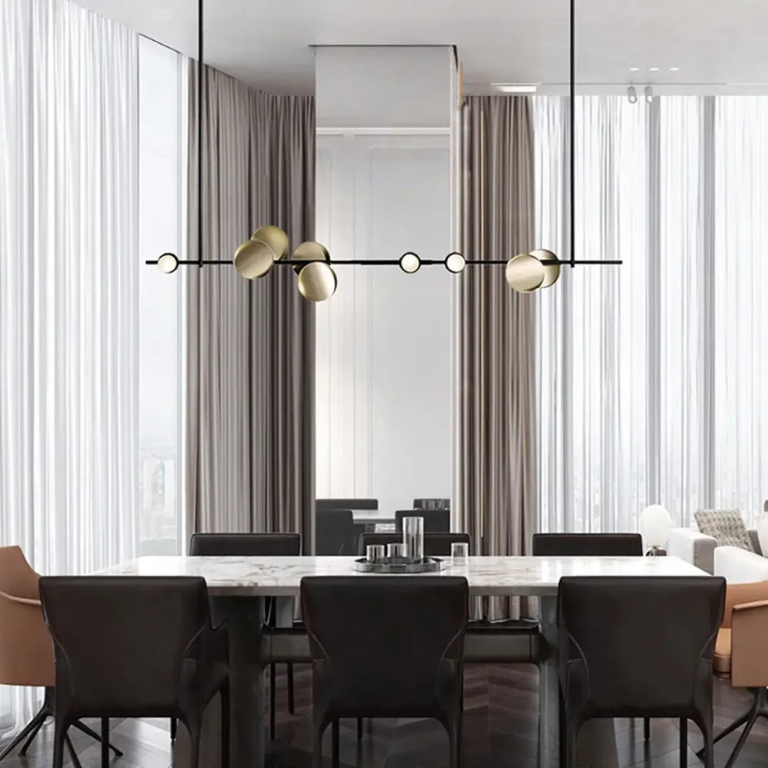 Suspension luminaire koumi en métal noir et sphère dorée moderne suspendue au-dessus d’une table en marbre