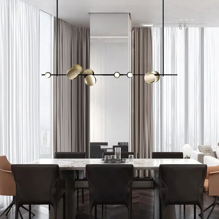 Suspension luminaire koumi en métal noir et sphère dorée moderne suspendue au-dessus d’une table en marbre