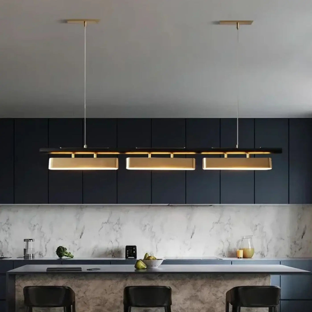 Suspension linéaire declina avec trois plaques dorées rectangulaires éclairées au-dessus dîlot de cuisine moderne