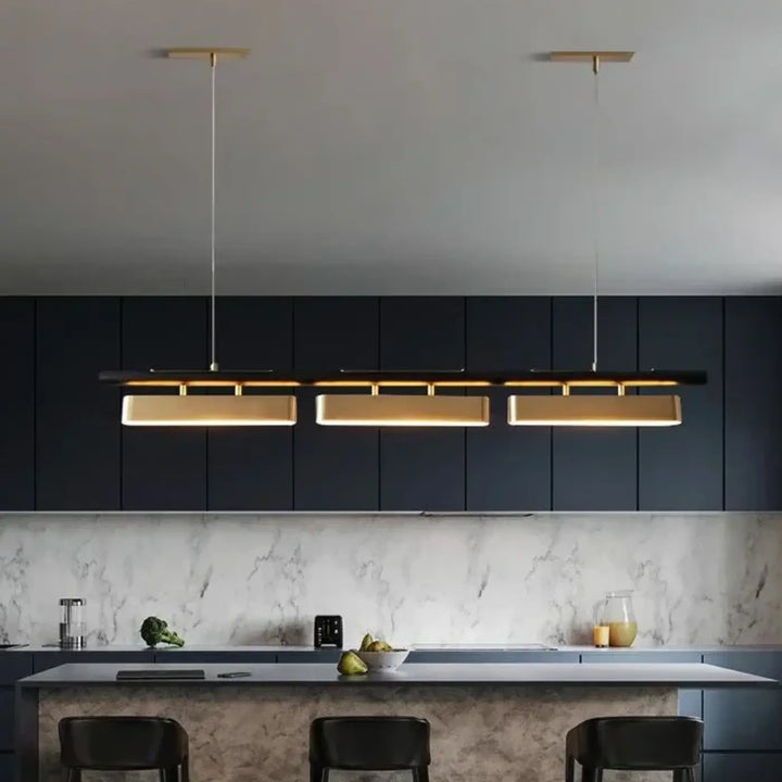 Suspension linéaire declina avec trois plaques dorées rectangulaires éclairées au-dessus dîlot de cuisine moderne