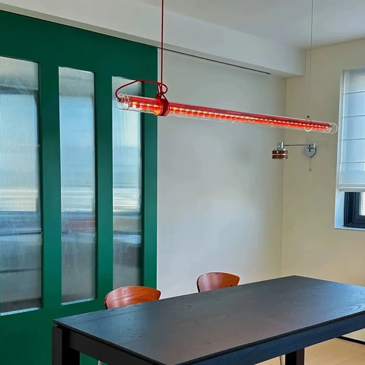Suspension luminaire nushia en verre soufflé rouge avec led intégrées et câble tressé suspendue au-dessus d’une table à manger