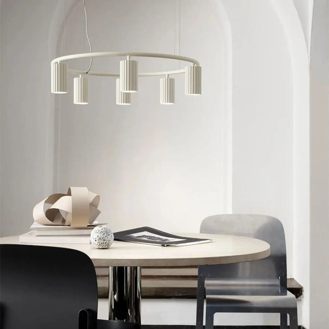 Suspension luminaire minimaliste zynth blanche circulaire avec cylindres texturés au-dessus dune table à manger épurée