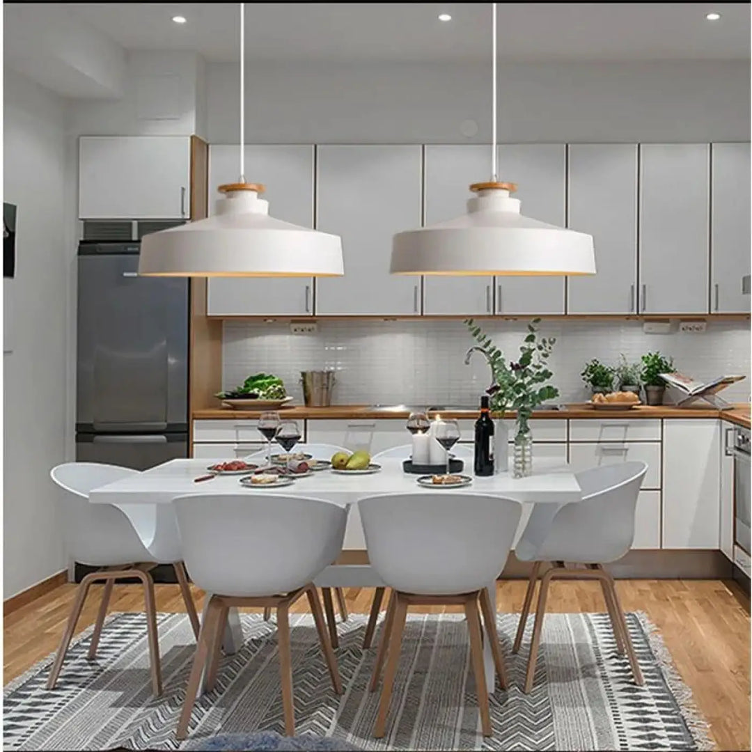 Deux suspensions luminaires minimalistes blanches avec accents en bois clair suspendues au-dessus d’une table à manger