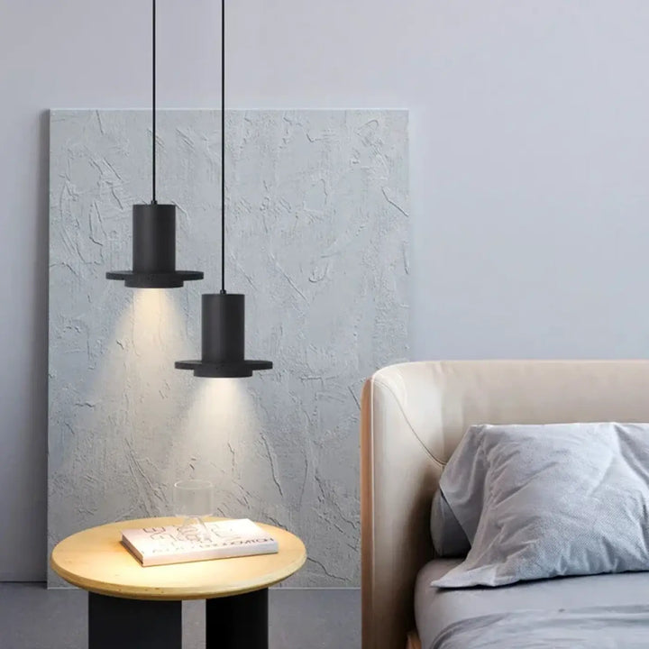 Deux suspensions luminaire danys cylindriques noires avec bases plates en pierre trou noir suspendues au-dessus d’une salle à manger