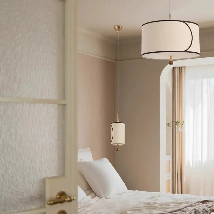 Suspension luminaire avril avec abat-jour cylindrique en tissu blanc, bordure noire et ferrure métal doré