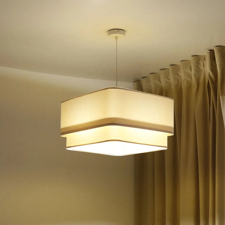 Suspension luminaire moderne kwadro duo velour blanc avec abat-jours en tissu beige superposés diffusant une lumière chaude