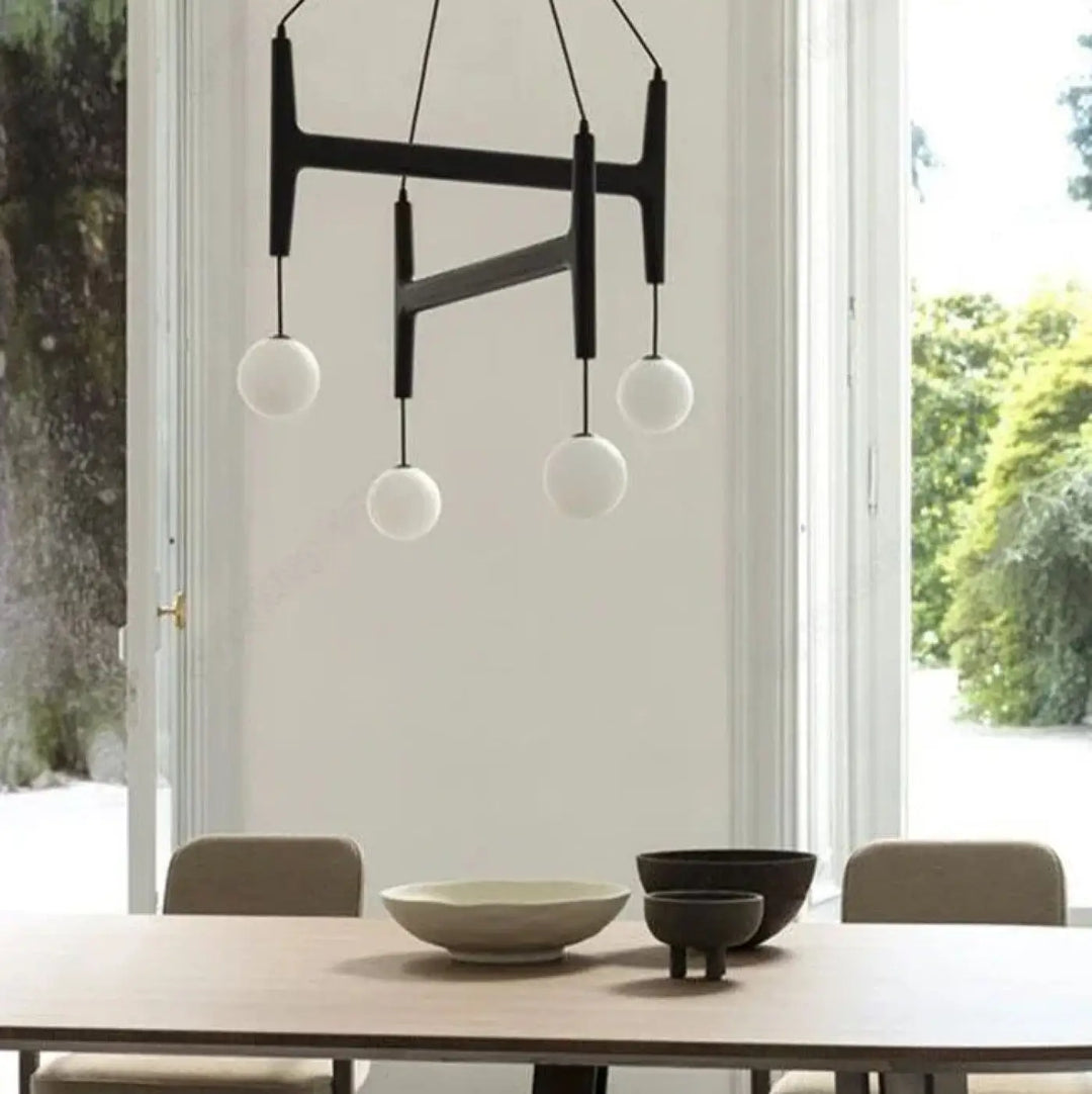 Suspension luminaire gradia noir en forme géométrique avec quatre globes en verre blanc pour besoin d’ouvrir espace
