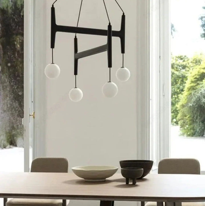Suspension luminaire gradia noir en forme géométrique avec quatre globes en verre blanc pour besoin d’ouvrir espace