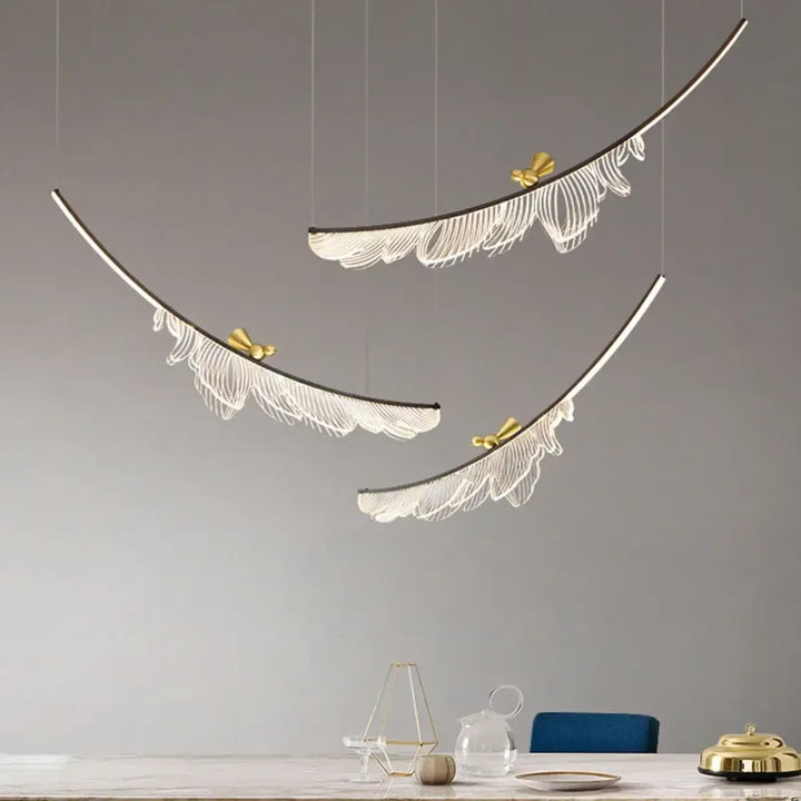 Suspension luminaire moderne jian avec trois luminaires plume courbés blancs et accents dorés suspendus au plafond