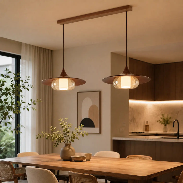 Suspension luminaire aurea avec effet cuivre, abat-jour en verre et fixation en bois au-dessus d’une table à manger