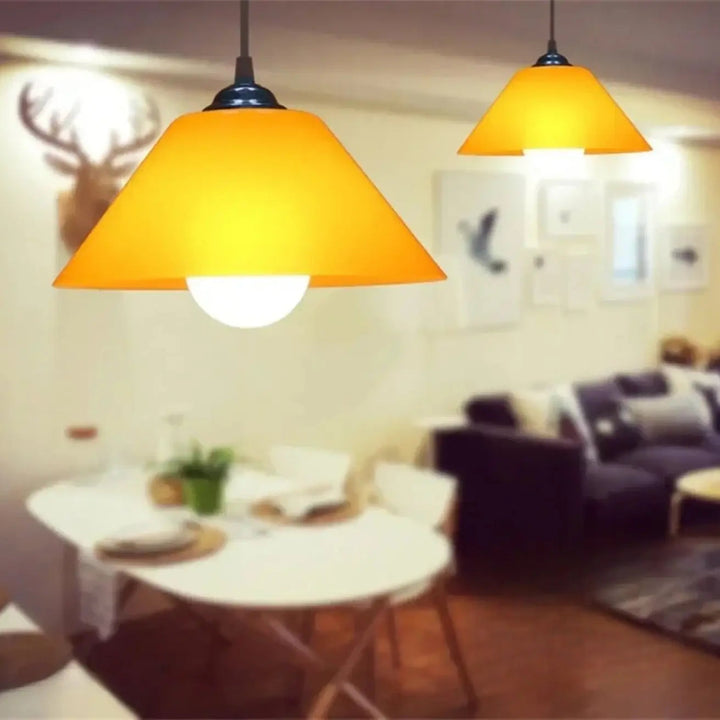 Suspension luminaire delta avec forme conique jaune chaud et fixation métal noir pour décoration intérieure au-dessus dune table à manger