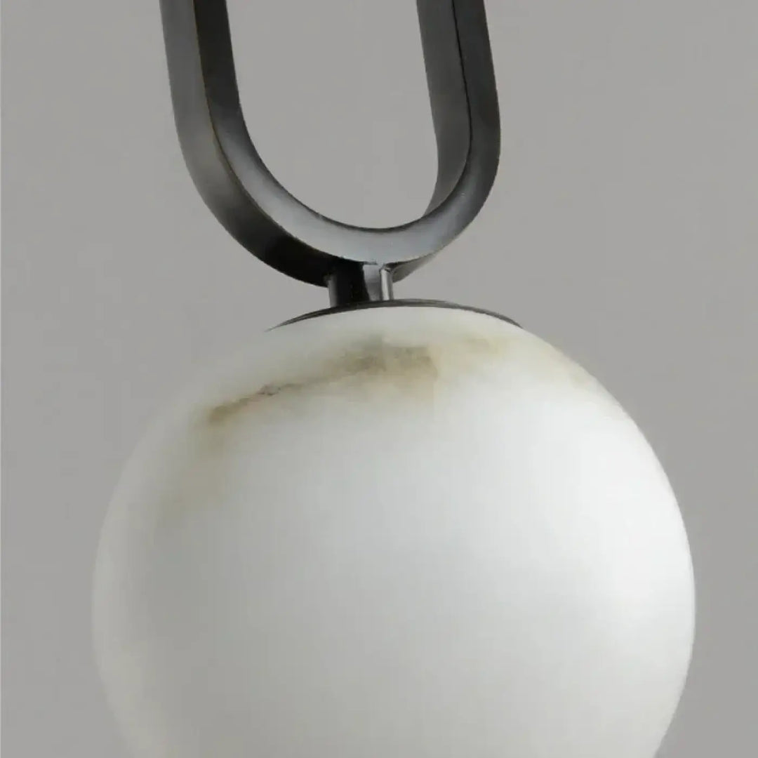 Suspension luminaire marbria avec une structure u en métal noir mat et une sphère en marbre blanc veiné gris