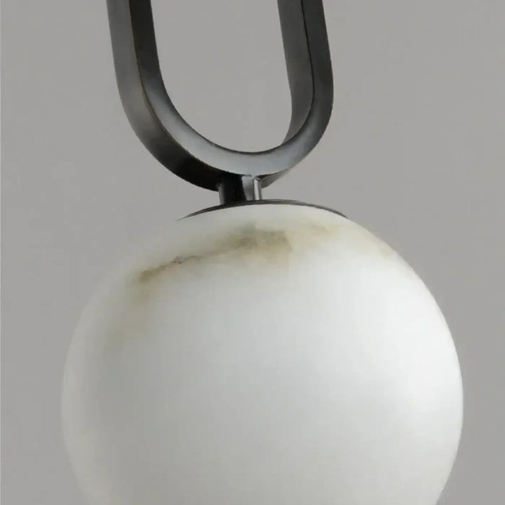 Suspension luminaire marbria avec une structure u en métal noir mat et une sphère en marbre blanc veiné gris