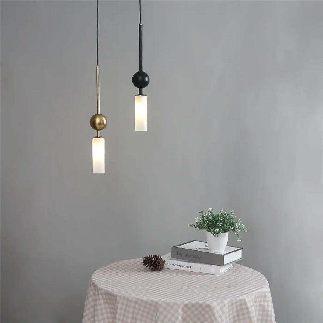 Suspension luminaire krysta avec deux boules métalliques minimalistes en laiton et noir suspendues au-dessus d’une table
