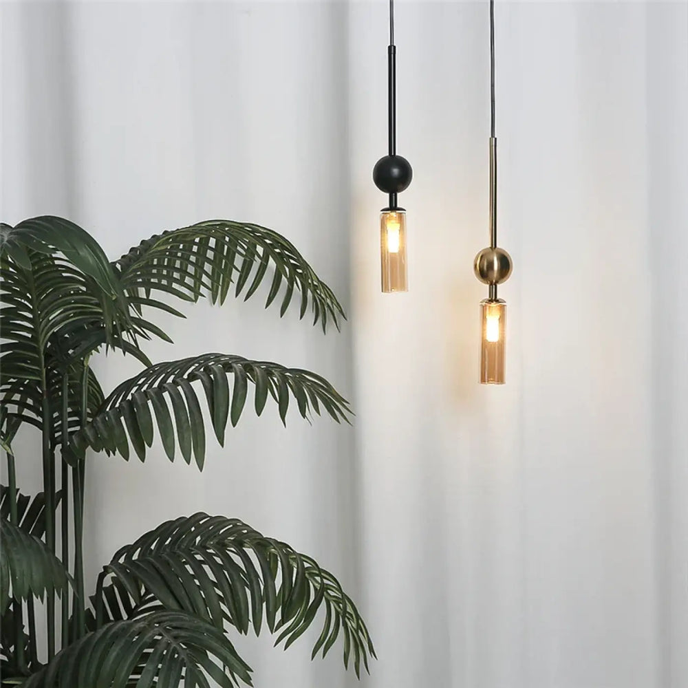 Suspension luminaire krysta avec deux boules métalliques noire et dorée et abat-jour cylindrique en verre transparent