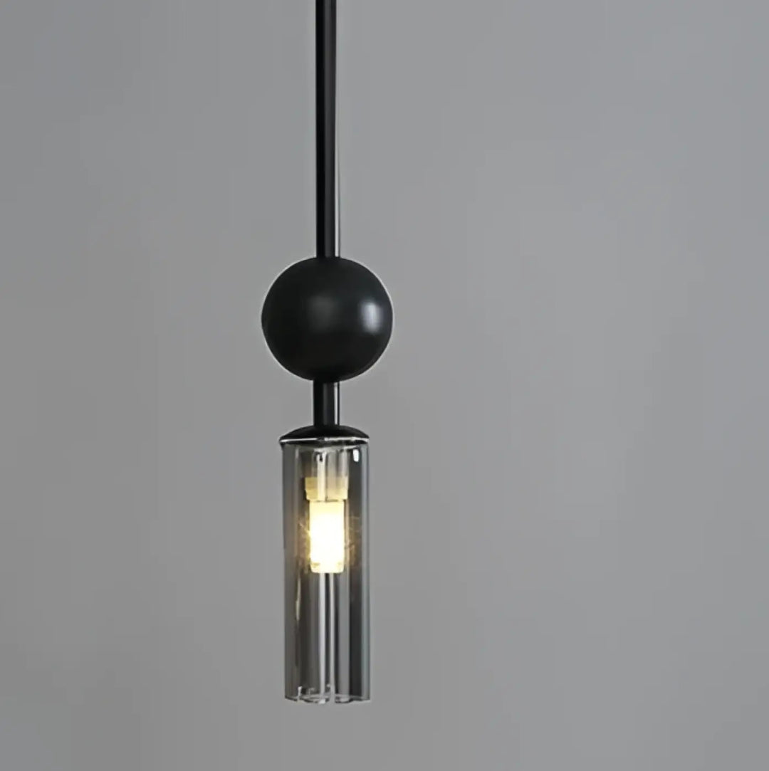 Suspension luminaire krysta avec boule métallique noire et cylindre en verre clair abritant lampoule