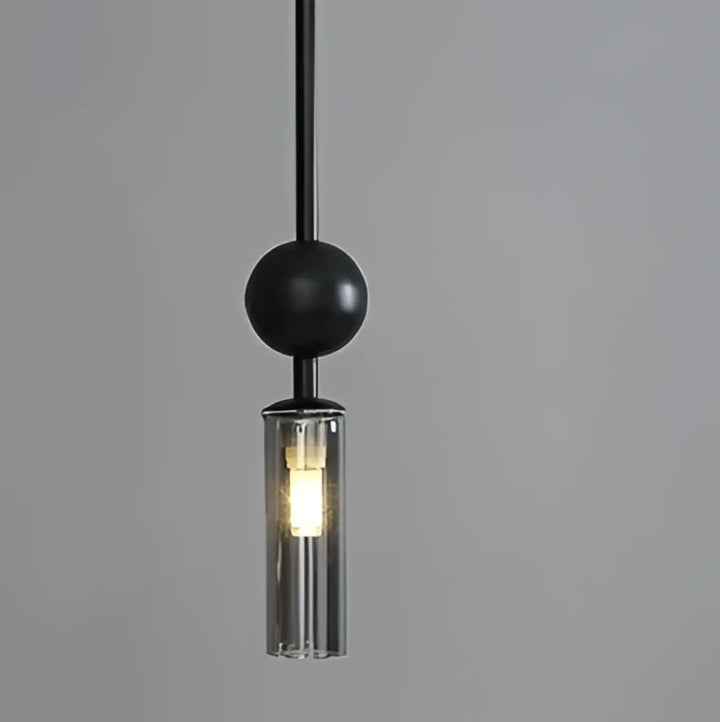 Suspension luminaire krysta avec boule métallique noire et cylindre en verre clair abritant lampoule