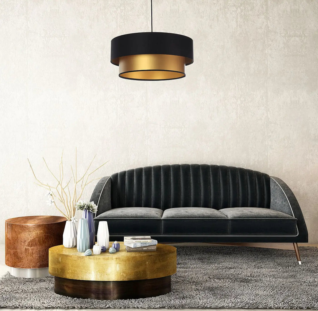 Suspension luminaire duo noire et dorée avec canapé en velours noir à dossier capitonné et coussins gris