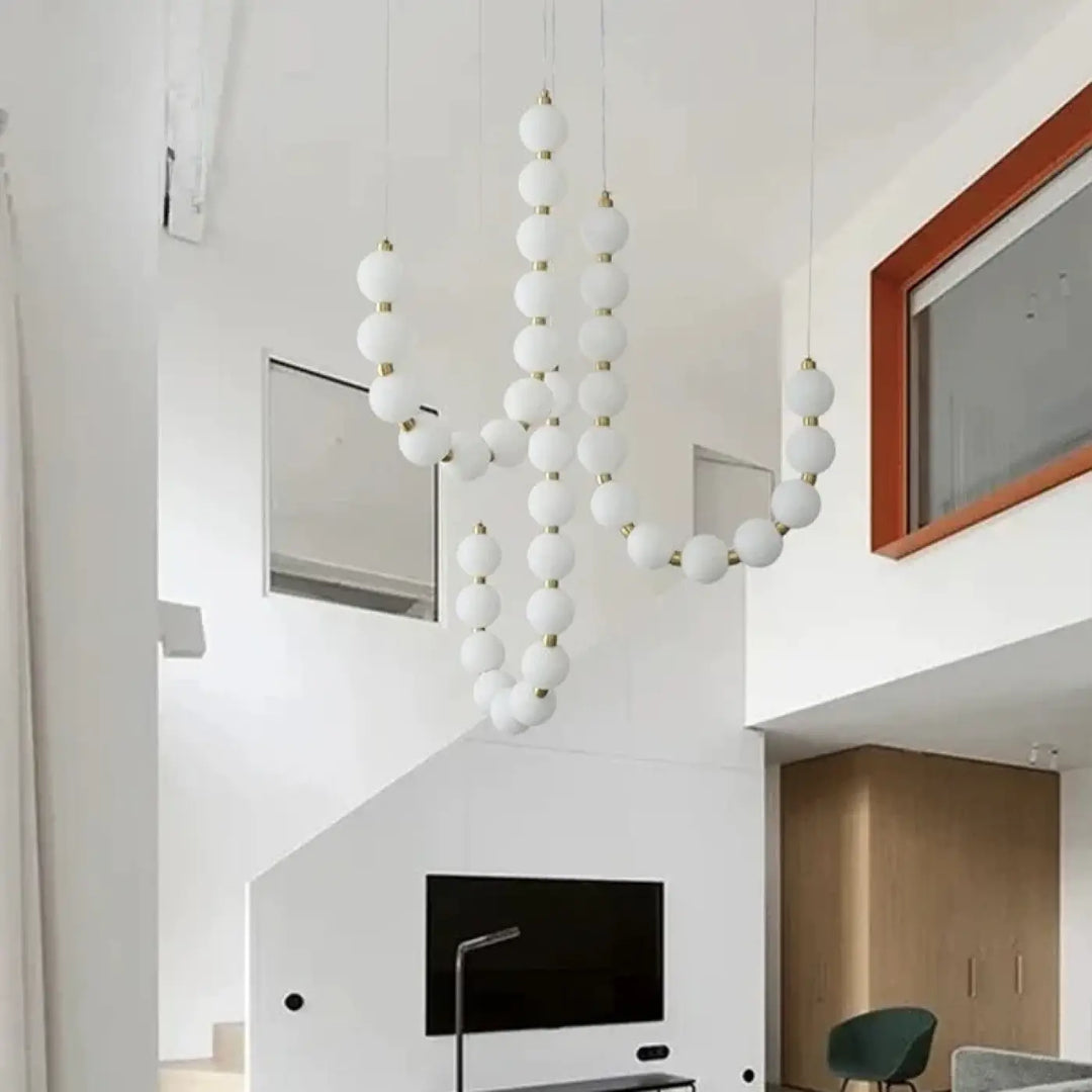 Suspension luminaire perles blanches avec connecteurs dorés offrant une ambiance douce et élégante