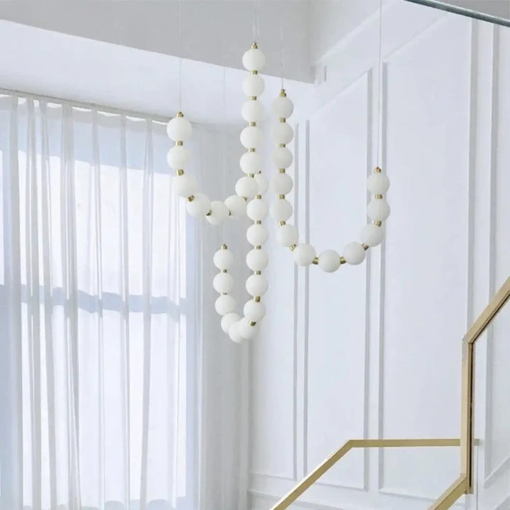 Suspension luminaire perlita sphérique blanche avec accents dorés pour créer une ambiance douce perles blanches