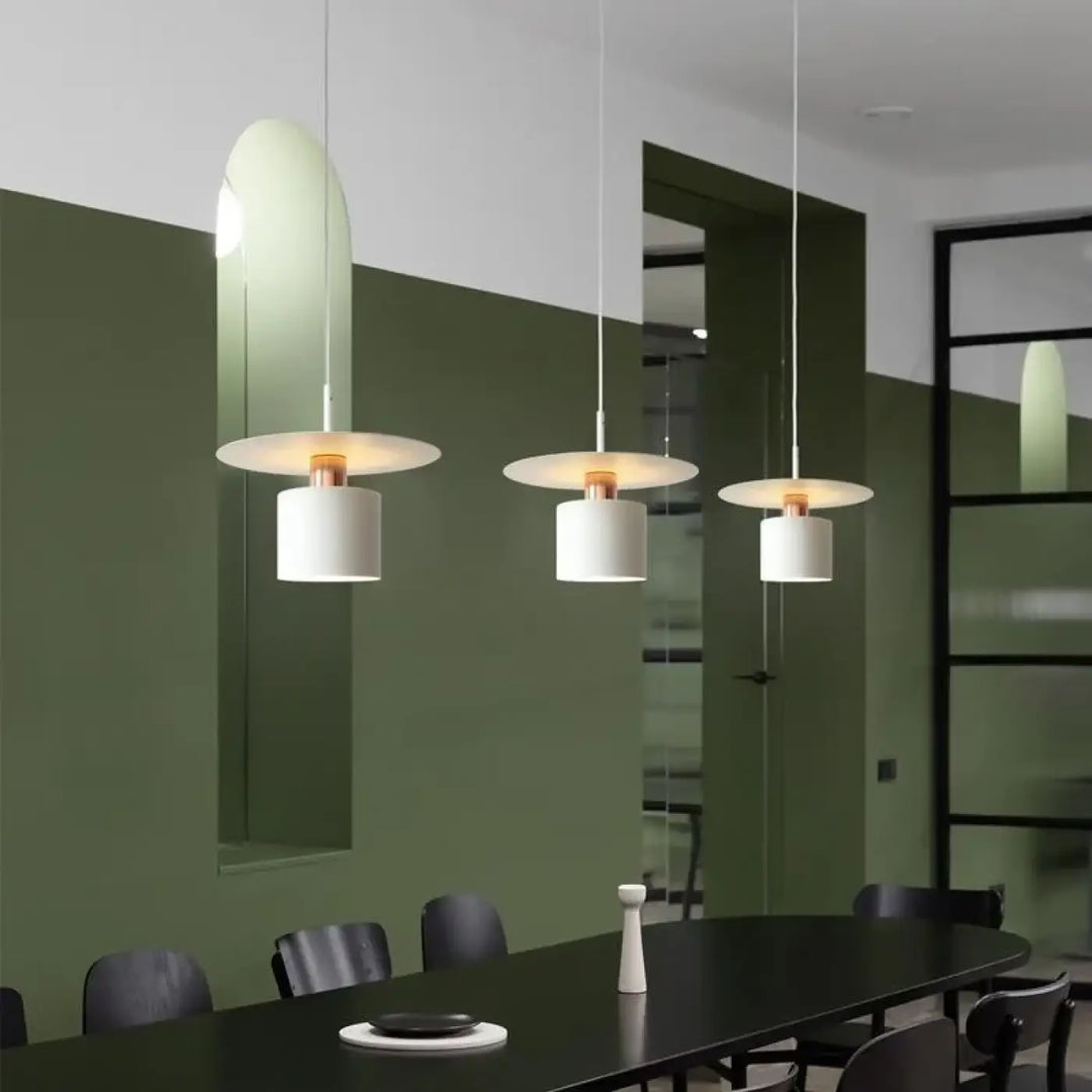 Suspension luminaire bougy avec trois suspensions raffinées en verre incurvé et abat-jour cylindrique blanc au-dessus d’une table sombre