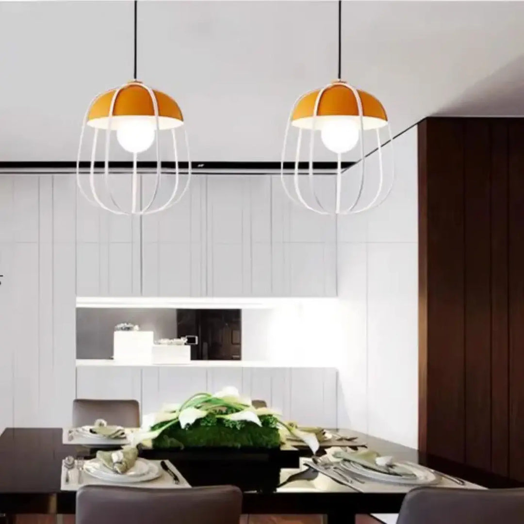 Suspension luminaire caldera avec deux abat-jours orange et armatures cageblanche effet rétro au-dessus dune table à manger