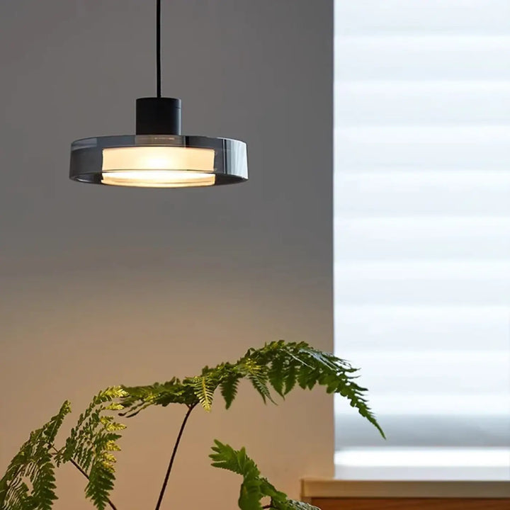 Suspension luminaire moderne noire avec anneau chrome et verre teinté diffusant une lumière chaude ronde