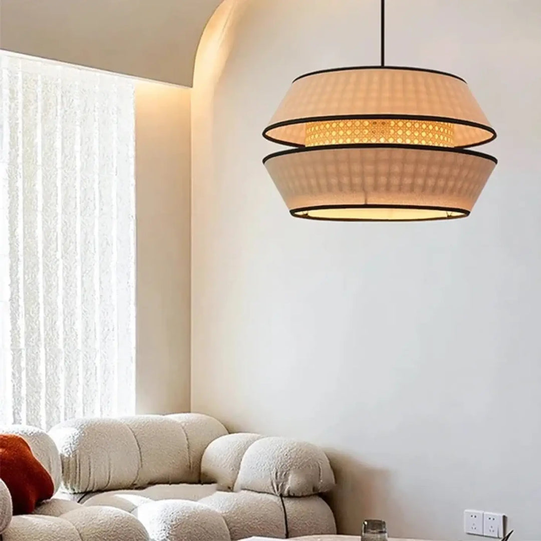 Suspension luminaire ambra en rotin naturel beige avec abat-jour circulaire superposé et bord noir qui contribue à créer une ambiance chaleureuse