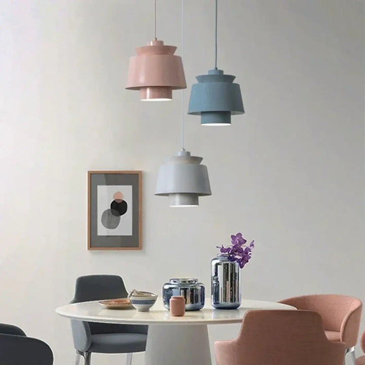 Suspension luminaire pendila avec luminaires suspendus en pastel à étages au-dessus d’une table à manger moderne