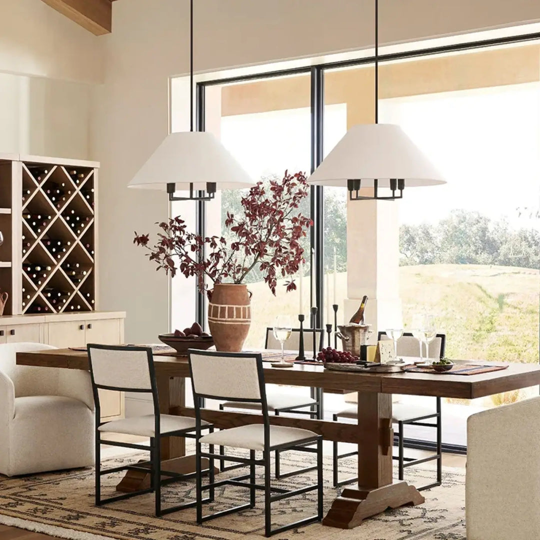 Suspension luminaire tissuni suspendue au-dessus d’une table à manger rustique en bois foncé avec pieds tréteaux robustes