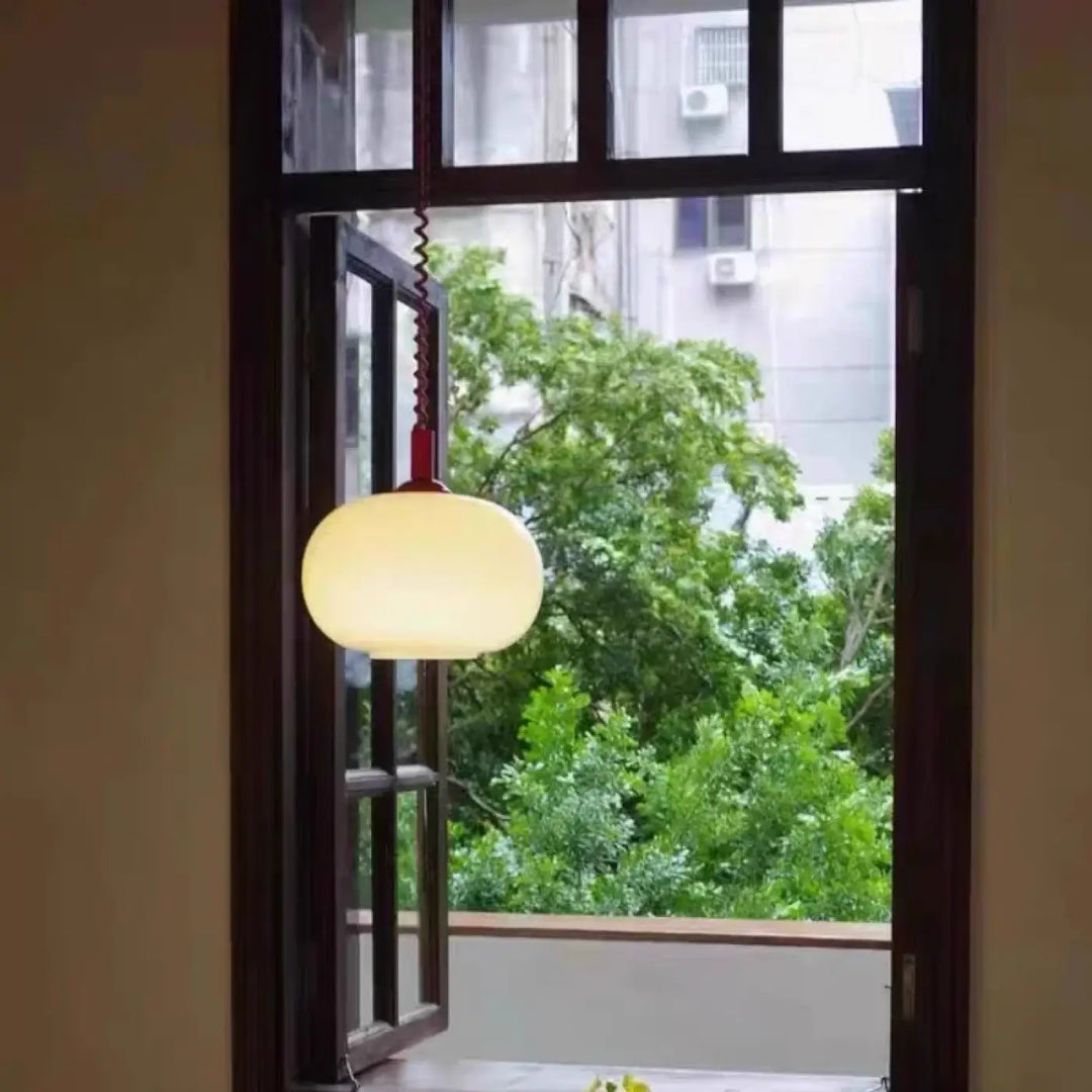 Suspension luminaire pendira avec verre blanc sphérique, cadre en bois foncé et câble spiralé rouge chaleureux
