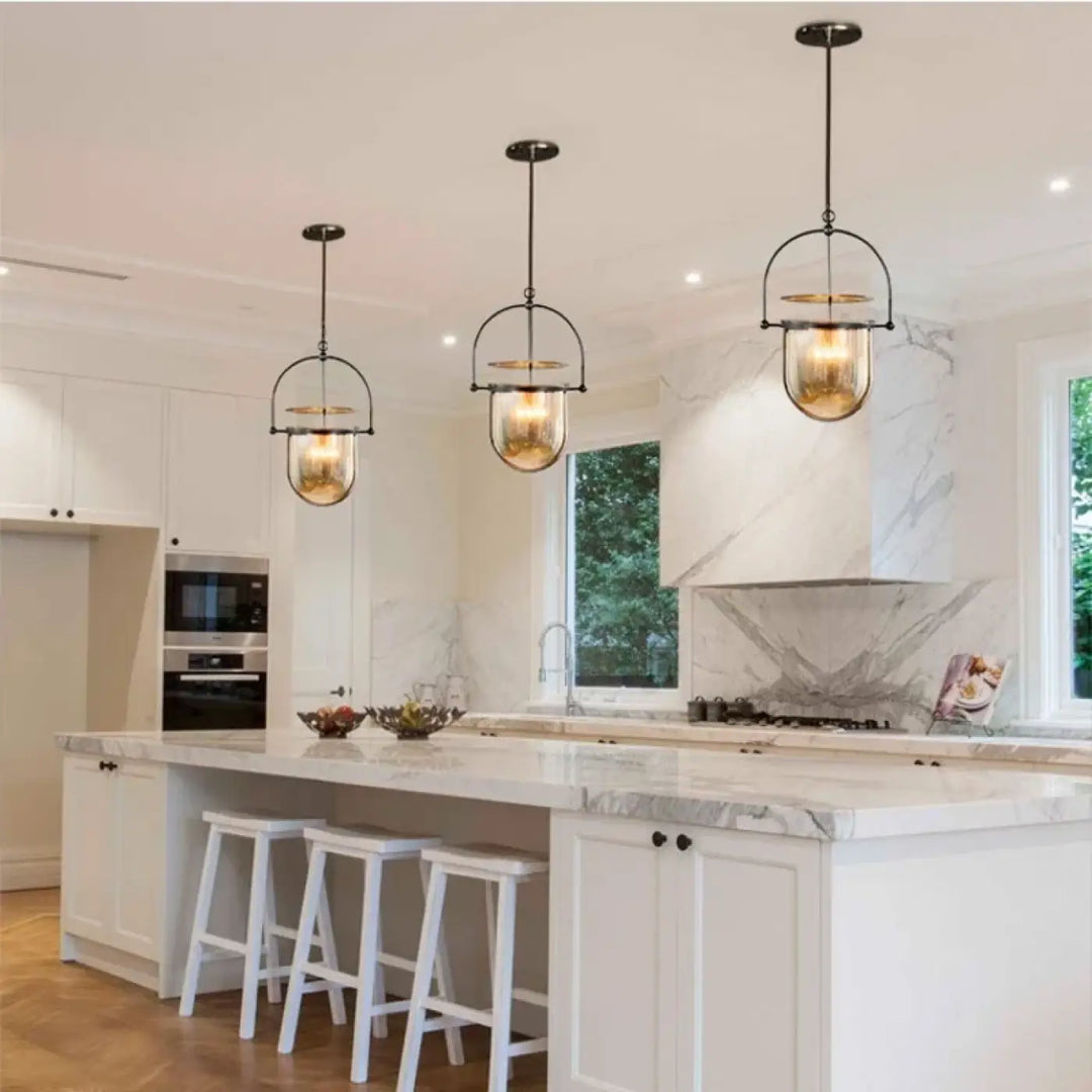 Trois suspensions lumineuses elysia en métal noir et ambre avec ampoules led au dessus dîlot en marbre blanc