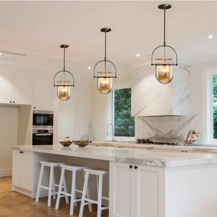 Trois suspensions lumineuses elysia en métal noir et ambre avec ampoules led au dessus dîlot en marbre blanc