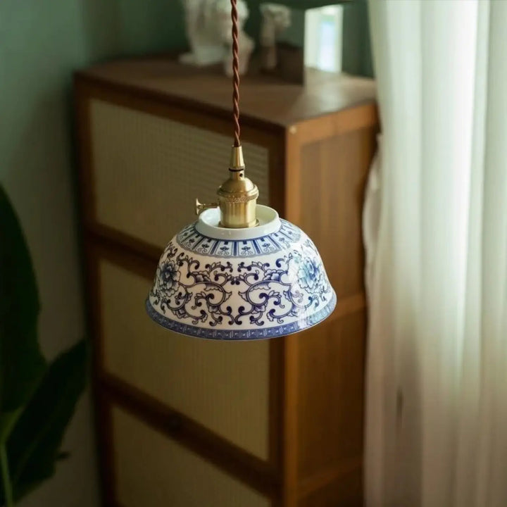 Photos montrent une suspension luminaire nara en porcelaine bleue et blanche avec motifs floraux suspendue par un cordon torsadé