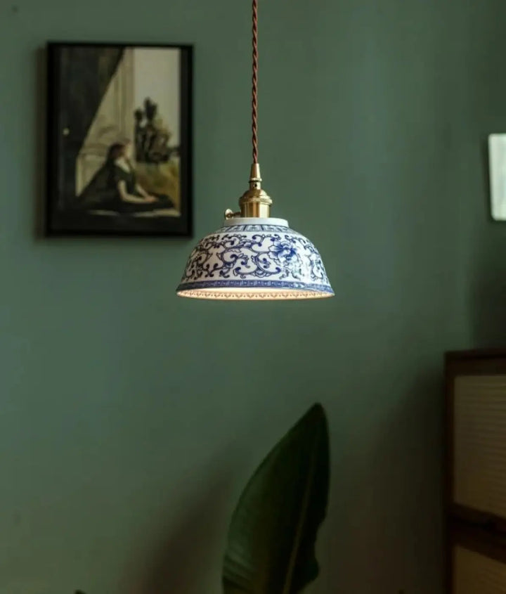 Photos montrent une suspension luminaire nara en porcelaine bleue et blanche avec motifs floraux et fixation en laiton