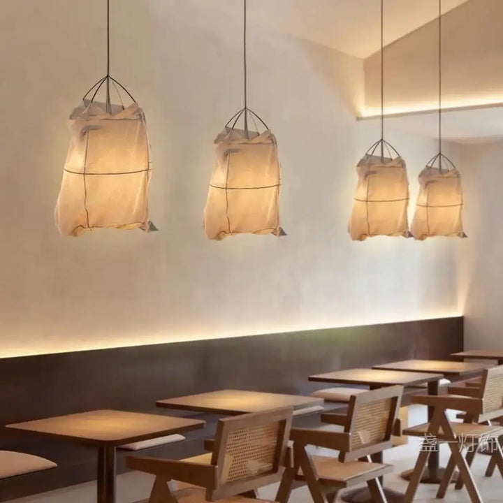 Suspension luminaire lima avec quatre lanternes en tissu beige diffuses et cadre métal noir style scandinave