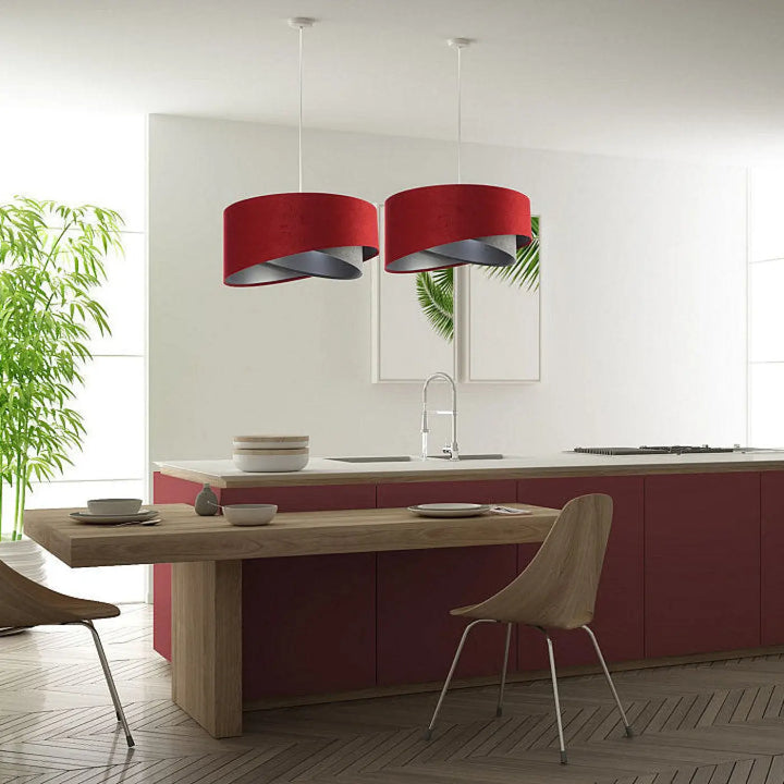 Deux suspensions luminaires cylindriques en tissu bordeaux avec détail argenté chic au-dessus dune île de cuisine