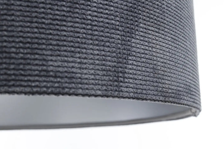 Suspension luminaire glamour structural velour en tissu graphite avec abat-jour texturé au-dessus d’une table