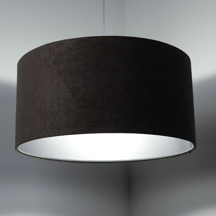 Suspension luminaire avec abat-jour cylindrique noir en tissu marron texturé et intérieur argent réfléchissant participe à créer une ambiance élégante