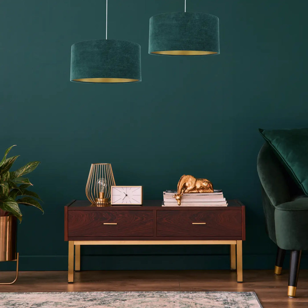Suspension luminaire en velours vert foncé avec intérieur doré au style moderne chic au-dessus d une console en bois