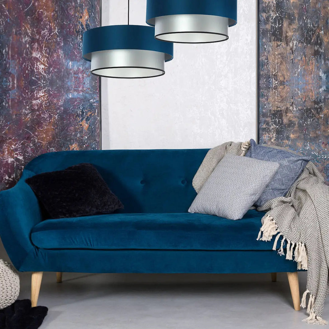 Deep blue velvet sofa with tufted back and light wood legs complementing suspension luminaire turquoise duo design